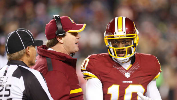 Washington Redskins head coach Jay Gruden (C) talks to Redskins quarterback Robert Griffin III (10) in the second half against the Philadelphia Eagles at FedEx Field. The Redskins won 27-24. Mandatory Credit: Geoff Burke-USA TODAY Sports
